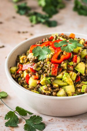 Lentil salad with avocado and red pepper on light background, vertical