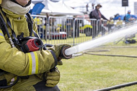 Photo for Close up photograph of high velocity water being sprayed by a fire fighter from a fire hose and nozzle onto an adjacent fire incident - Royalty Free Image