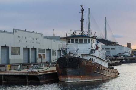 Foto de Port of Long Beach, California, United States - February 12, 2023: old boat docked, view of the port shown in late afternoon. with overcast sky. - Imagen libre de derechos
