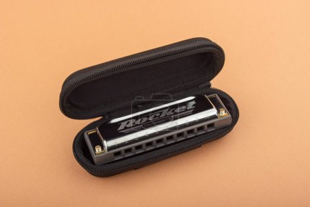 Téléchargez les photos : Hohner professionnel diatonique Rocket harmonica se trouve dans un boîtier noir ouvert. Sur un fond brun clair - en image libre de droit