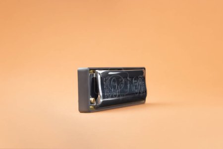 Téléchargez les photos : Hohner Rocket harmonica diatonique professionnel sur le côté. Sur un fond brun clair - en image libre de droit