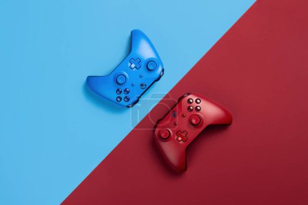 Foto de Dos mandos xbox se encuentran uno frente al otro sobre un fondo azul y rojo - Imagen libre de derechos