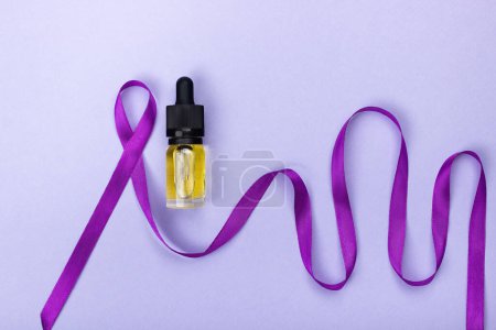 Photo for Glass bottle with CBD oil extract next to a purple epilepsy sign made from a ribbon whose other end depicts brain activity. Alternative treatments for epilepsy - Royalty Free Image