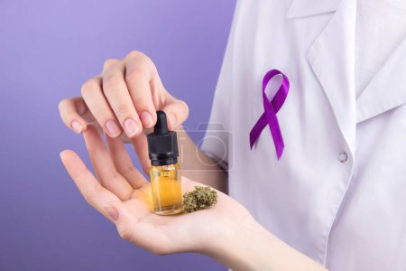 Photo for In the hands of a doctor, a glass bottle with a pipette with an extract of cbd oil, in the palm of his hand, a dry bud of medical marijuana.  Alternative treatment with medical cannabis.  On the doctor's chest is a sign of the fight against cancer - Royalty Free Image