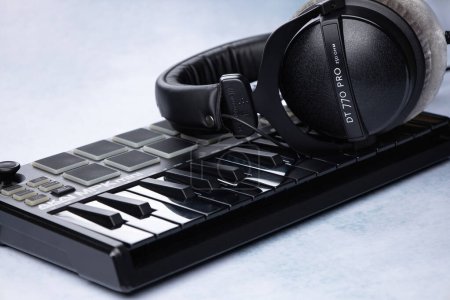 Foto de Auriculares cerrados de la marca beyerdynamic dt 770 se encuentran en el teclado midi AKAI MPK mini mk2, sobre un fondo claro - Imagen libre de derechos