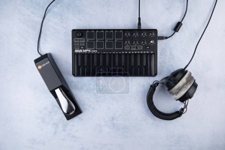 Foto de Estilo piano Sustain Pedal M-Audio La marca SP-2 se encuentra junto al teclado midi AKAI MPK mini mk2, sobre un fondo claro y auriculares cerrados del beyerdynamic dt 770 - Imagen libre de derechos