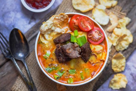 Photo for Soto Betawi is an Indonesian soup made of coconut milk and fill with beef, potatoes, and tomatoes - Royalty Free Image