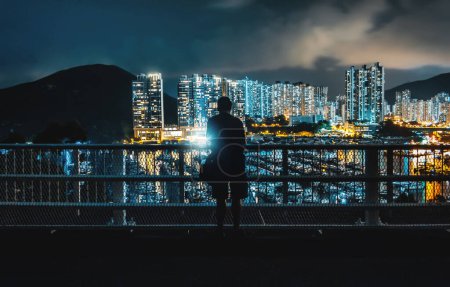 Photo for Night Scene of Silhouette of person in front of Modern Contemporary Skyscrapers at Marina with Piers and Yachts in Aberdeen, Hong Kong - Royalty Free Image