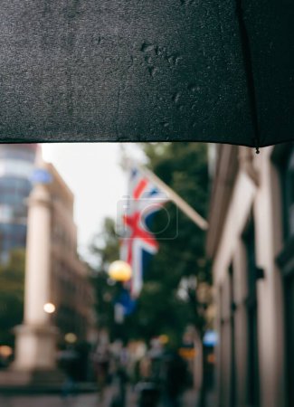 Bandera británica borrosa en tiempo lluvioso con paraguas húmedo en Londres, Reino Unido