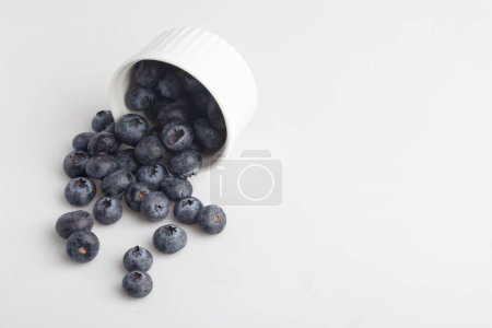Téléchargez les photos : Bleuets dans une tasse sur fond blanc - en image libre de droit