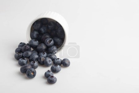 Téléchargez les photos : Bleuets dans une tasse sur fond blanc - en image libre de droit
