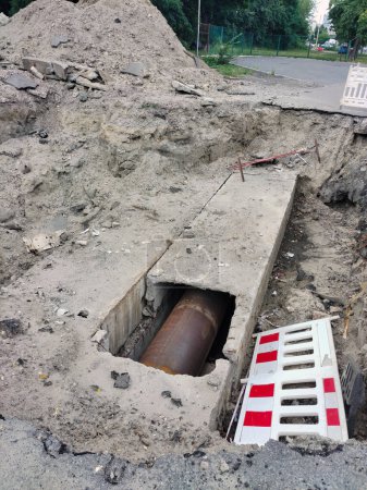 Téléchargez les photos : Il y a un tuyau d'égout dans un trou creusé sur la route, qui est en cours de réparation par les services routiers de la ville - en image libre de droit