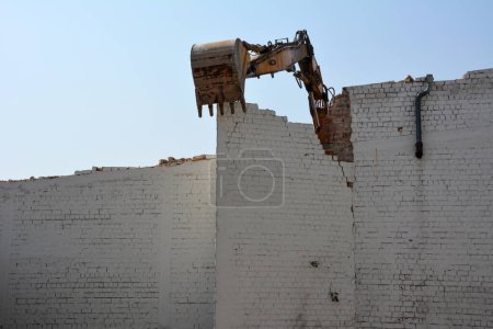 Photo for Construction site with the dismantling of the wall of an old building on a city street with an excavator on the background of the sky. Reconstruction and renovation of cities - Royalty Free Image