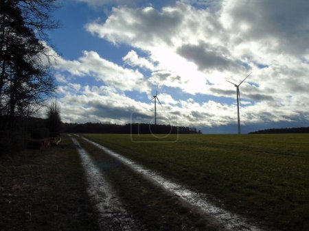 Téléchargez les photos : Les moulins à vent sont situés sur le terrain sous un ciel nuageux. Un chemin de terre longe le champ en perspective - en image libre de droit