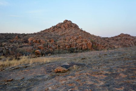 Rocky arid terrain with a small rocky hill under a blue sky. Desert landscape and nature