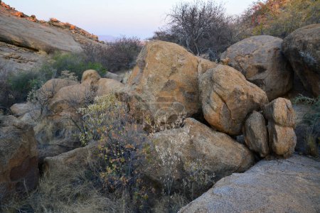 Rocky arid terrain with large boulders between rocky hills under a blue sky. Desert landscape and nature