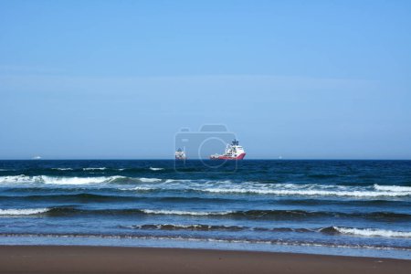 Industrial ships sail on the sea blue waves on the blue sea. Sea ship traffic and landscape