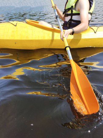 A boy in a kayak in a life jacket pulls an oar during training. Side view. Active sports life and recreation