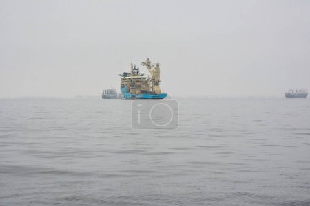An oil rig service ship floats in the sea with other ships in the distance. Maritime transport and industry