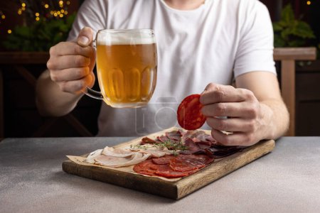 Foto de Un hombre tiene un vaso de cerveza y un aperitivo. En un restaurante - Imagen libre de derechos