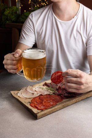 Foto de Un hombre tiene un vaso de cerveza y un aperitivo. En un restaurante - Imagen libre de derechos