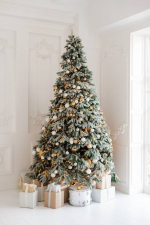 Téléchargez les photos : Une chambre joliment décorée avec un arbre de Noël avec des cadeaux en dessous. Noël intérieur. arbre lumineux magique, nouvel an. Concentration sélective douce. - en image libre de droit
