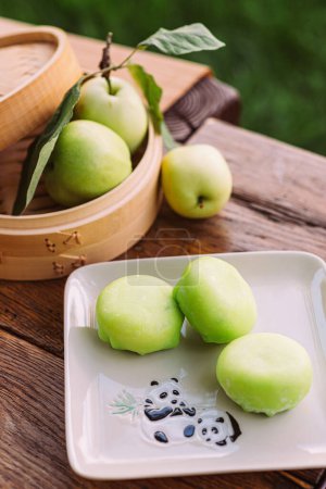 Téléchargez les photos : Une assiette de pommes vertes sur une table en bois à côté d'un panier de pommes, présentant une variété de produits frais et d'aliments naturels. Mochi asiatique dessert - en image libre de droit