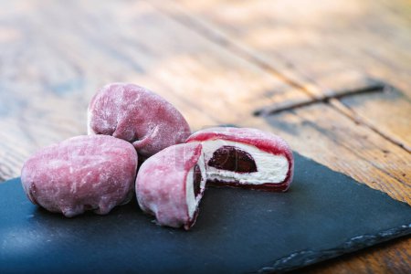 Photo for Three purple mochi balls made from natural ingredients,resembling a fruit with a bite taken out of one.Mochi is a staple food often made from plantbased ingredients like rice and root vegetables.Mochi - Royalty Free Image