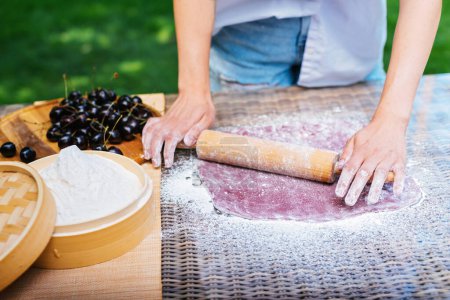 Photo for A person is using a wooden rolling pin to flatten dough on a table. The hardwood rolling pin contrasts with the wooden table, creating a rustic cooking scene. Mochi asian dessert - Royalty Free Image