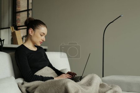 Téléchargez les photos : Jeune pigiste travaillant de la maison sur son ordinateur portable - en image libre de droit