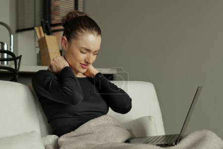 Photo for Portrait of a young woman with a neck pain rubbing massaging tensed muscles after long computer work study in incorrect posture - Royalty Free Image