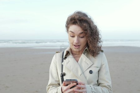Téléchargez les photos : Portrait d'une jeune femme surprise regardant un téléphone voir de mauvaises nouvelles ou photo - en image libre de droit