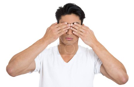 Foto de Hombre con una camiseta blanca cubriéndose los ojos con las manos sobre fondo blanco. - Imagen libre de derechos