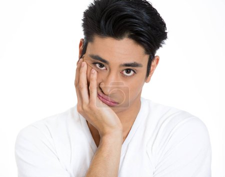 portrait of a sleepy young man, funny guy placing head on hand, unhappy looking at camera feeling bored, isolated on white background. 
