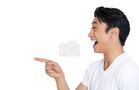 Gros plan vue de côté portrait d'un jeune homme, riant, pointant du doigt quelqu'un ou quelque chose, isolé sur fond blanc