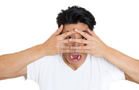 Photo for Closeup portrait of a scared, shy man covering face with hands fingers, peering through with wide eyes isolated on white background - Royalty Free Image