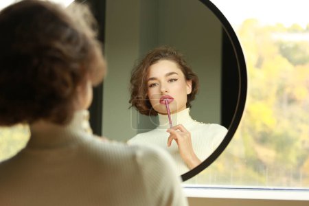 young beautiful woman looking in a mirror applying make up