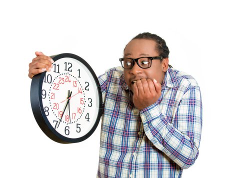 Foto de El joven estresado se queda sin tiempo mirando el reloj de pared - Imagen libre de derechos