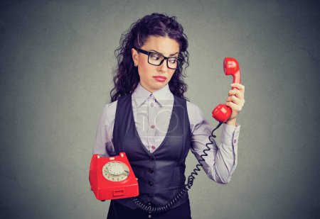 Young businesswoman looking at a red phone with a suspicious expression