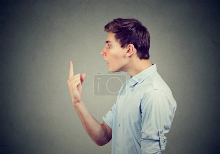 Side profile of a shocked young man looking at his finger