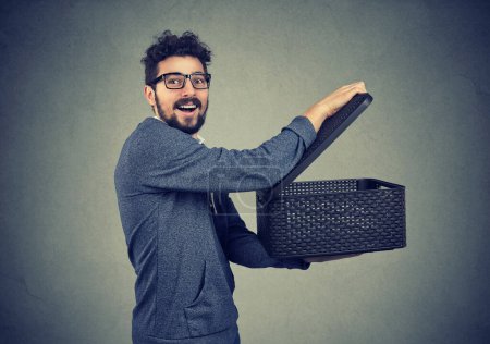 Photo for Happy young man opening storage box and sharing its contents - Royalty Free Image