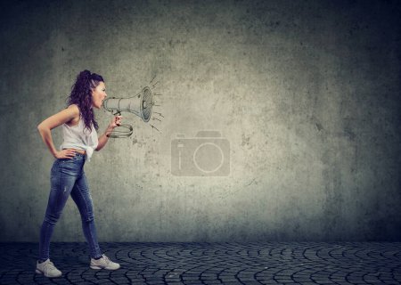 Téléchargez les photos : Jeune femme criant en mégaphone isolé sur fond de mur gris - en image libre de droit