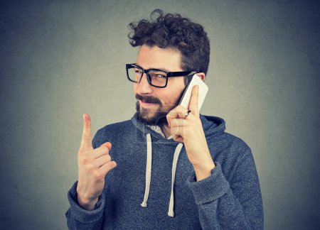 Photo for Man with deceiving face expression talking on a phone tells lies - Royalty Free Image