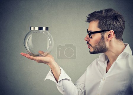 Téléchargez les photos : Jeune homme tenant et regardant un pot en verre vide - en image libre de droit