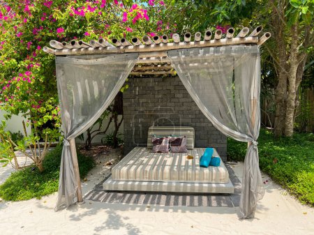 Foto de Fushifaru, Maldivas - 3 de mayo de 2022: Amplia cama al aire libre para una relajación previa o posterior al tratamiento en el Heylhi Spa en el complejo boutique Fushifaru en el atolón de Lhaviyani, Maldivas. - Imagen libre de derechos