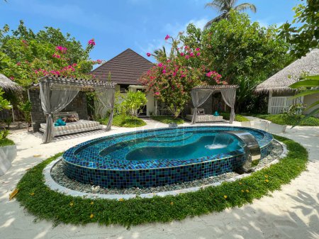 Foto de Fushifaru, Maldivas - 3 de mayo de 2022: Hermosa piscina y grandes camas al aire libre para una relajación previa o posterior al tratamiento en el Heylhi Spa en el complejo boutique Fushifaru en el atolón de Lhaviyani, Maldivas. - Imagen libre de derechos
