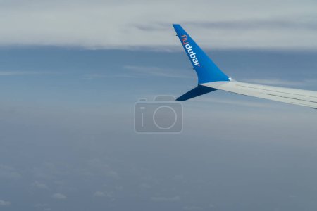 Photo for Dubai, United Arab Emirates - 8th May, 2022 - Midair view of the winglet of a Flydubai flight, Boeing 737 Max with a sky and clouds background. - Royalty Free Image