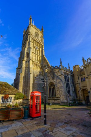 Photo for Cirencester, UK - October 17, 2022: View of the Church of St. John the Baptist, red phone box and directional signs, in Cirencester, the Cotswolds region, England, UK - Royalty Free Image