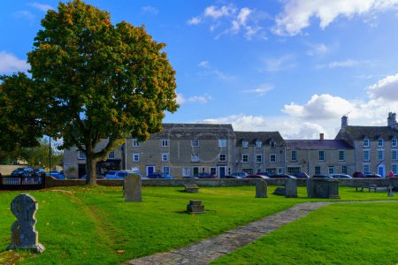 Photo for Fairford, UK - October 17, 2022: View of the church cemetery, houses and visitors, in Fairford, the Cotswolds region, England, UK - Royalty Free Image