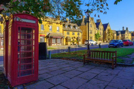 Photo for Broadway, UK - October 18, 2022: Street view with red phone box, local businesses, locals, and visitors, in Broadway, Cotswolds region, England, UK - Royalty Free Image